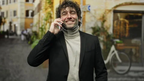 Man smiling in city street while talking on smartphone wearing a dark suit .. Stock Footage 310034004