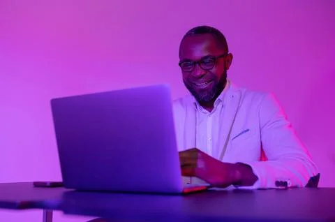 Man smiling at the computer at work. A black programmer works using a lapto Stock Photos