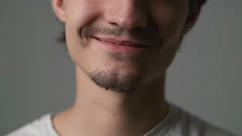 Man smiling with eyes closed in quiet happiness against gray background Stock Footage 347029336