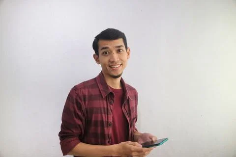 A man smiling happy while holding a handphone Foto stock
