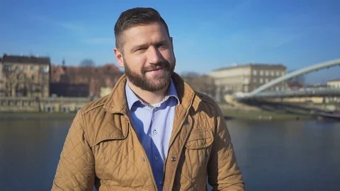 Man smiling, laughing at camera on background of the river, sunny day Vídeos de archivo 72709540