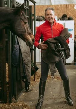 Man smiling looking at camera with saddle next to his horse. Stock Photos