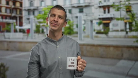 Man smiling in outdoor setting holds coffee mug with boss slogan and makes .. Stock Footage 312342225