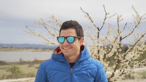 Man smiling with sunglasses. Looking at camera, nature on the background Видео 93014447