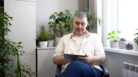 Man Smiling While Browsing Tablet at Home Photos