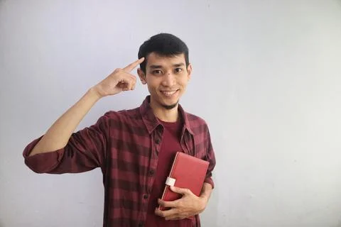 Man smiling while holding a book and pointing to his head Stock Photos