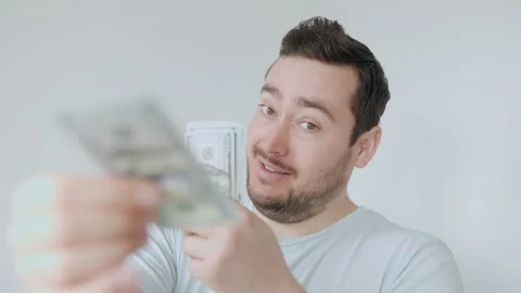 Man smiling while holding cash in bright indoor setting Video stock 306260223
