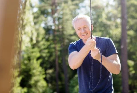 Man Smiling While Holding Rope In Forest Foto stock