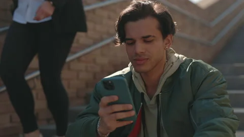 Man smiling while looking on mobile screen outdoors Stock Footage 163910521