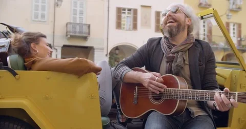 Man smiling while playing guitar music with girlfriend.Woman listening to Видео 82589590