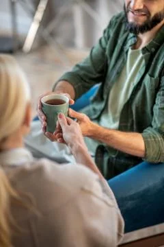 Man smiling while taking cup of tea from psychologist Stock Photos