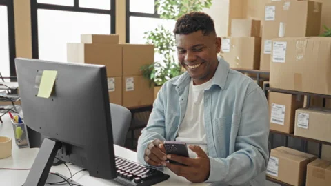 Man smiling while tapping smartphone and handling parcel boxes at desk in b.. Stock Footage 337369834