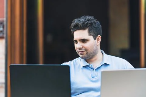 Man smiling while trading cryptocurrencies wit two laptops Stock Photos