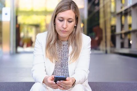 Man smiling while using a red smartphone against a bright blue background Stock Photos