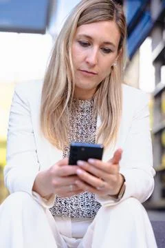Man smiling while using a red smartphone against a bright blue background Stock Photos