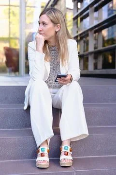 Man smiling while using a red smartphone against a bright blue background Stock Photos