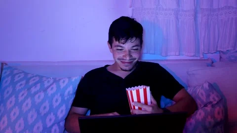 Man smiling while watching a movie on his computer Stock Footage 289992553
