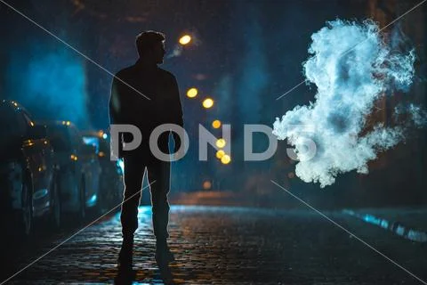 The man smoke in the cloud of smoke. Evening night time. Telephoto lens shot Stock Photos