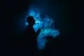 The man smoke an electric cigarette against the background of the blue light Photo