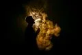 The man smoke an electric cigarette against the background of the flame Photo