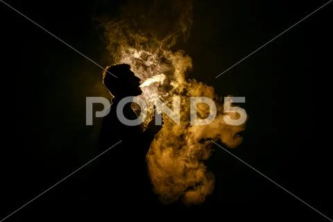 The man smoke an electric cigarette against the background of the flame Stock Photos