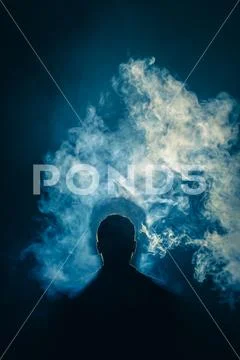 The man smoke an electric cigarette on the background of a bright light Stock Photos