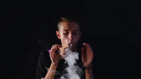 The man smoke electric cigarette on the dark background Stock Footage
