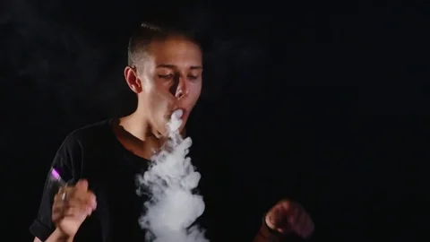 The man smoke electric cigarette on the dark background Stock Footage