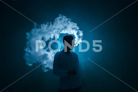 The man smoke an electrical cigarette on the dark background Stock Photos