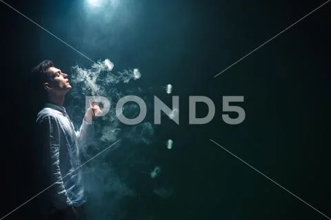 The man smoke an electrical cigarette with a ring and on the black background Stock Photos