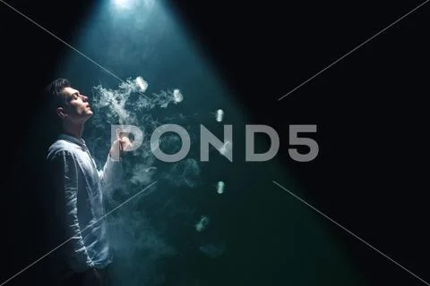 The man smoke an electrical cigarette with a ring and on the black background Stock Photos