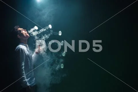 The man smoke an electrical cigarette with a ring and on the black background Stock Photos