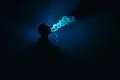 The man smoke an electronic cigarette against the background of the blue ligh Photo