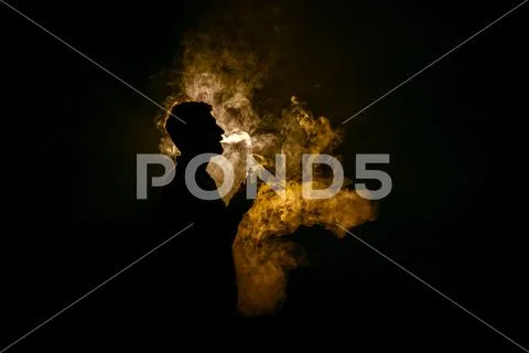 The man smoke an electronic cigarette against the background of the flame Stock Photos