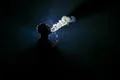 The man smoke an electronic cigarette against the background of the dark Photo