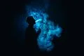 The man smoke an electronic cigarette against the background of the blue ligh Photo