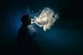 The man smoke an electronic cigarette on the background of the bright light Photo
