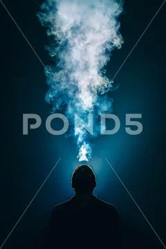 The man smoke an electronic cigarette on the background of bright light Stock Photos