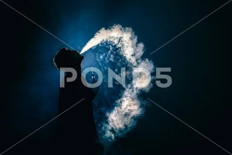 The man smoke an electronic cigarette on the background of the light Stock Photos
