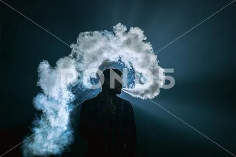 The man smoke an electronic cigarette on the bright light background Stock Photos