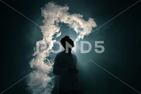 The man smoke an electronic cigarette on the dark background Stock Photos