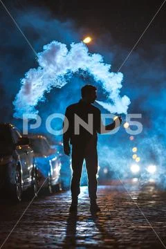 The man smoke electronic cigarette outdoor. Evening night time Stock Photos
