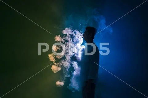 The man smoke an electronic cigarette with a ring against the dark background Stock Photos