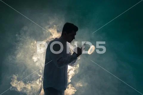 The man smoke an electronic cigarette with a ring on the dark background Stock Photos