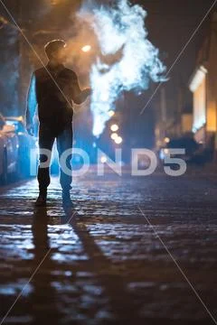 The man smoke electronic cigarette on the street. Evening night time Stock Photos