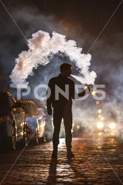 The man smoke electronic cigarette in the street. Evening night time Stock Photos