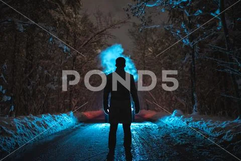 The man smoke on the snowy road in the dark forest. evening night time Stock Photos