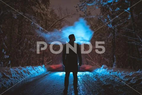 The man smoke on the snowy road in the forest. evening night time Stock Photos