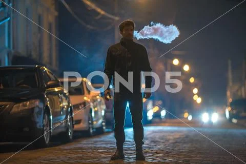The man smoke on the street. Evening night time. Telephoto lens shot Stock Photos