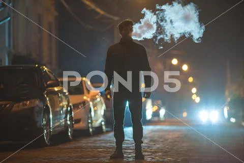 The man smoke on the street. Evening night time. Telephoto lens shot Stock Photos